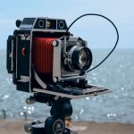 Старинная камера на штативе у каменистого берега